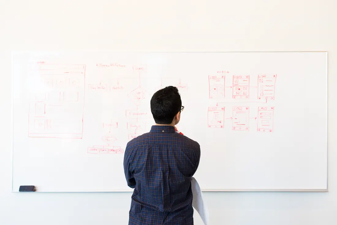 Engineer sketching a system architecture on a whiteboard